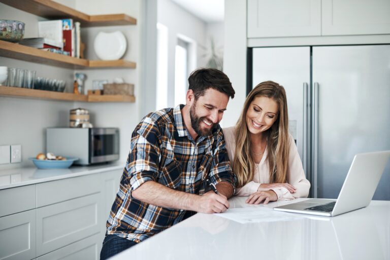 Shot of a young couple using a laptop and going through paperwork at home