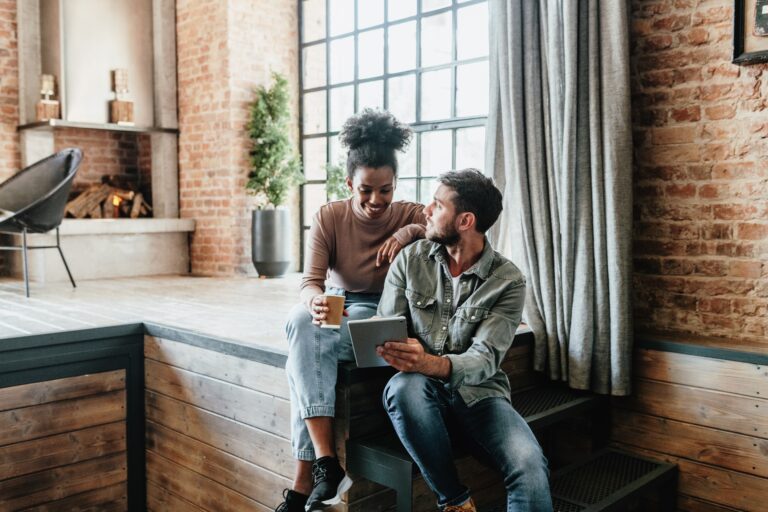 Happy couple in modern loft looking at tablet