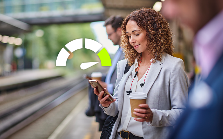 Woman standing at a train station looking at her phone with a credit score rating icon floating just above the phone's screen.